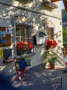 Eingangsbereich Landhaus Gritschacher mit bemalten Fensterrahmen und roten Blumen